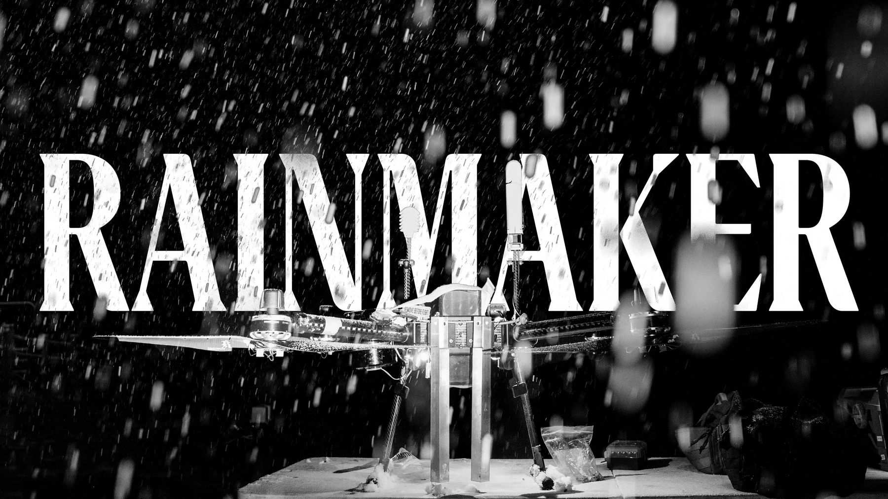 A Rainmaker drone on the ground in falling snow, the wordmark behind it.