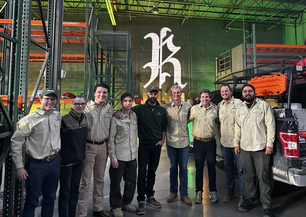 The Rainmaker team gathers in the warehouse beneath the blackletter R.